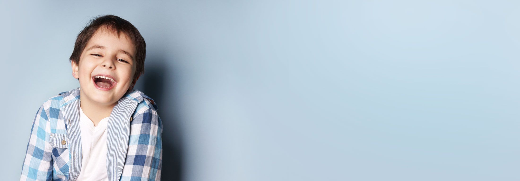 Junge mit kariertem Hemd lacht in die Kamera